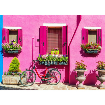 Red bicycle parked in front of a pink building with flower boxes. Burano Island Italy